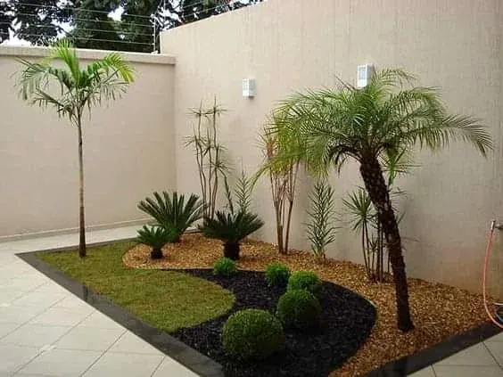 Jardim residencial com gramado, palmeiras e canteiro
