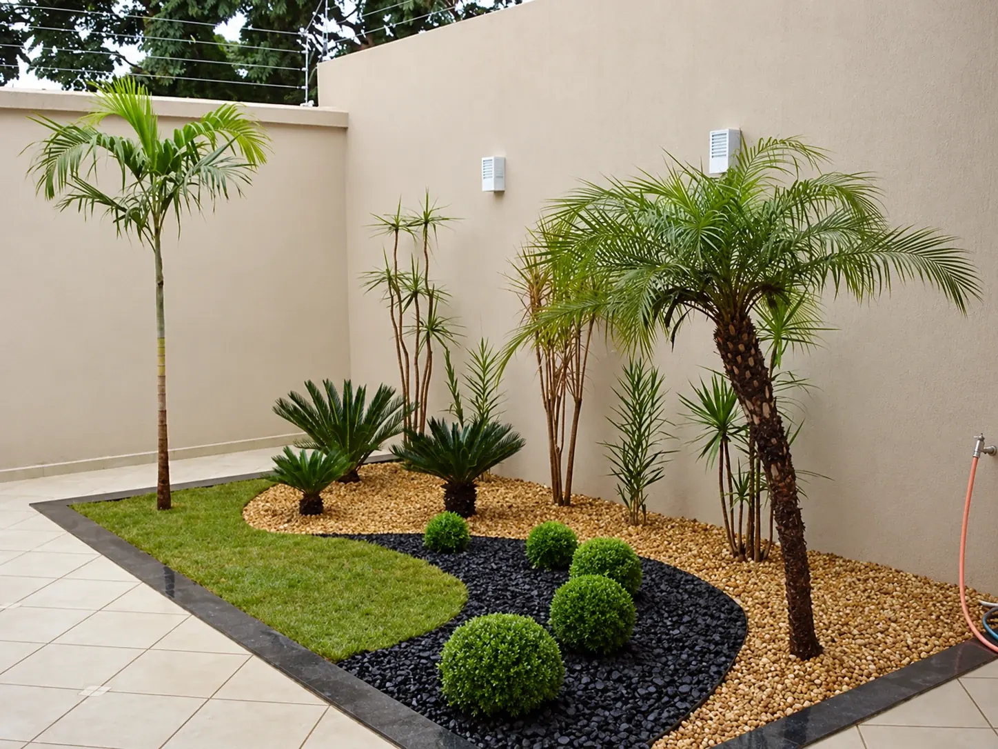 Jardim residencial com palmeiras, gramado e canteiros de seixos
